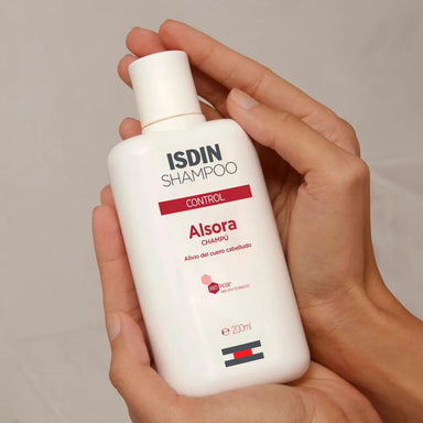 Manos sosteniendo el frasco de ISDIN Alsora Control Champú 200 ml